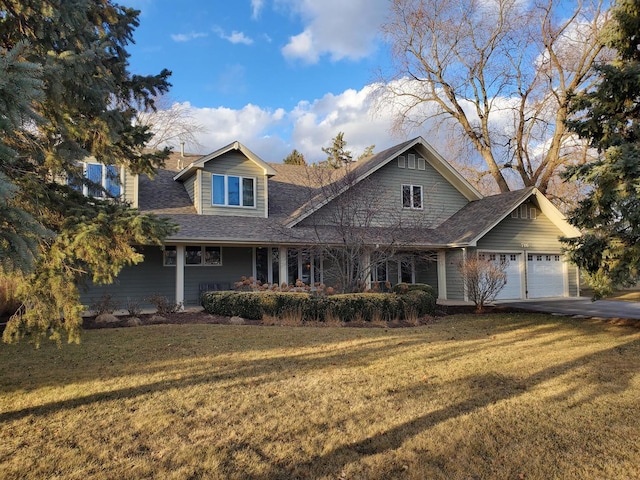 view of front of house featuring a front lawn, a garage, driveway, and a shingled roof