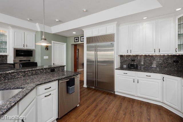 kitchen featuring backsplash, dark wood finished floors, decorative light fixtures, white cabinets, and stainless steel appliances