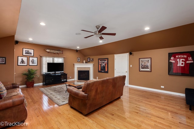 living area with light wood finished floors, ceiling fan, baseboards, lofted ceiling, and a fireplace