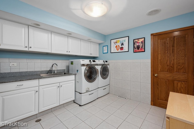 laundry area featuring a sink, washing machine and dryer, cabinet space, tile walls, and light tile patterned flooring