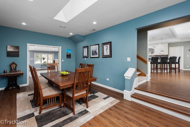 dining area featuring stairway, wood finished floors, baseboards, and a skylight