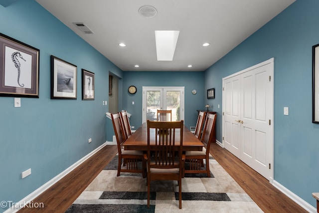 dining room featuring a skylight, baseboards, wood finished floors, and recessed lighting