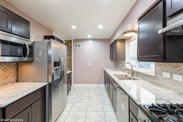 kitchen featuring appliances with stainless steel finishes, visible vents, a sink, and light stone counters