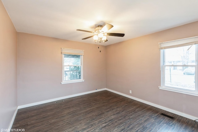 empty room with baseboards, visible vents, and dark wood-style flooring