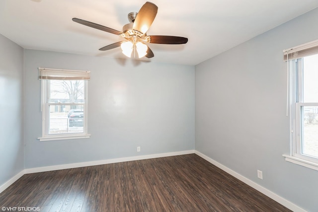 spare room featuring baseboards, ceiling fan, dark wood-style flooring, and a healthy amount of sunlight