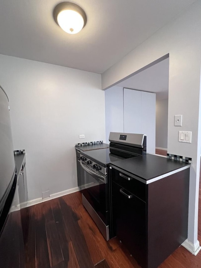 kitchen featuring modern cabinets, baseboards, dark wood-type flooring, and electric stove