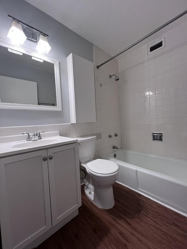 bathroom featuring visible vents, toilet, vanity, wood finished floors, and  shower combination