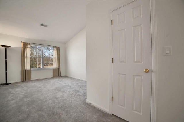 carpeted empty room with visible vents, lofted ceiling, and baseboards