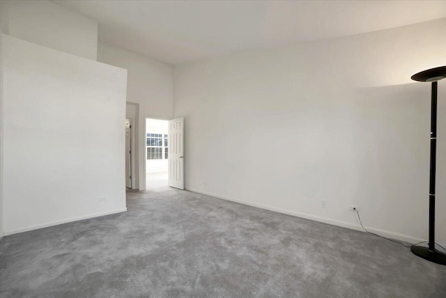 unfurnished room featuring a high ceiling, carpet flooring, and baseboards