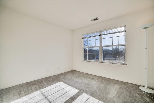 carpeted spare room with visible vents and baseboards