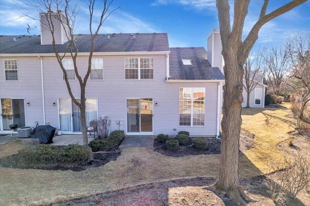 back of house featuring a chimney, a patio, and a shingled roof