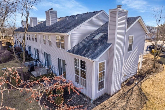 back of property featuring roof with shingles and a chimney