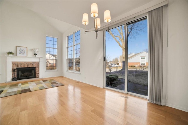 unfurnished living room featuring visible vents, a brick fireplace, baseboards, and wood finished floors