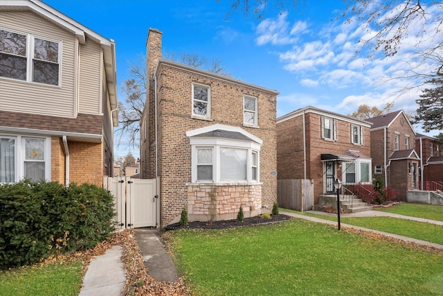 view of front of property with stone siding, a chimney, a gate, a front yard, and brick siding