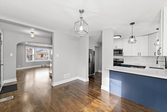 kitchen with arched walkways, stainless steel appliances, a sink, light countertops, and backsplash