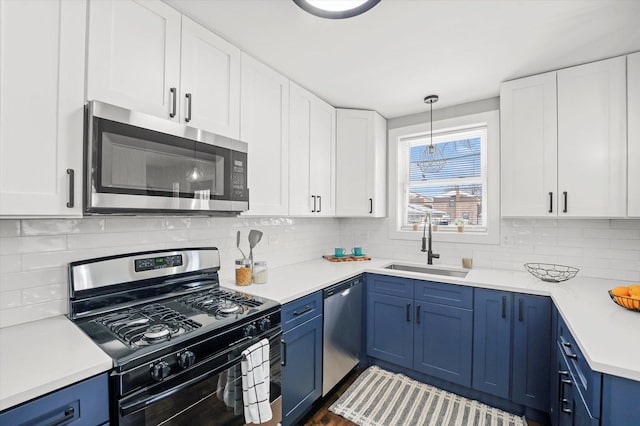 kitchen with blue cabinets, a sink, light countertops, appliances with stainless steel finishes, and tasteful backsplash