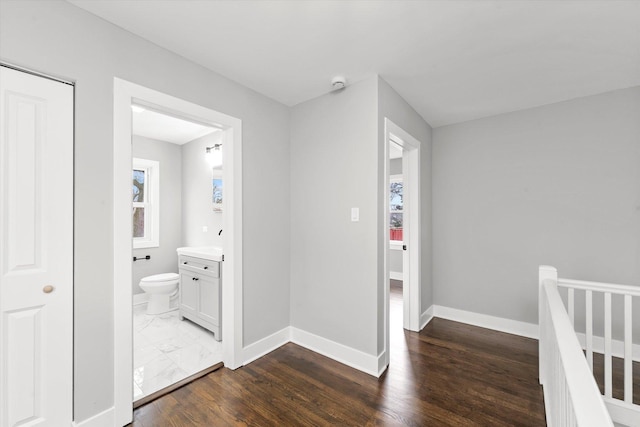 corridor featuring dark wood-style flooring, an upstairs landing, and baseboards