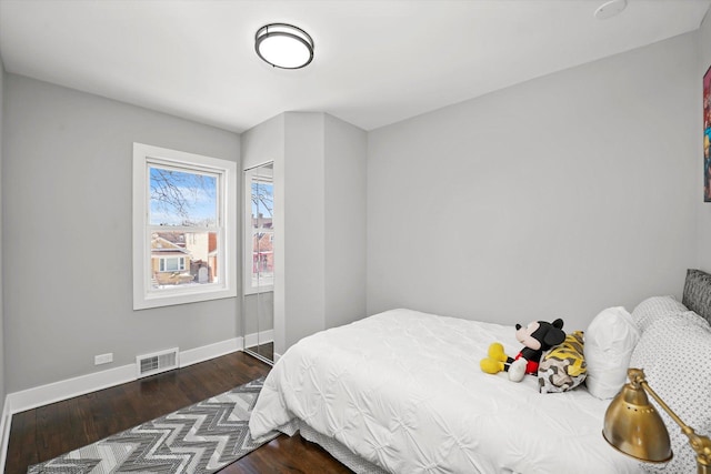 bedroom with visible vents, baseboards, and wood finished floors