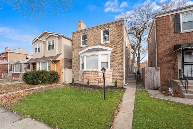 view of front of property featuring brick siding, a chimney, stone siding, and a front yard