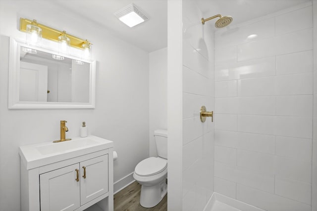 full bath featuring toilet, a tile shower, wood finished floors, and vanity