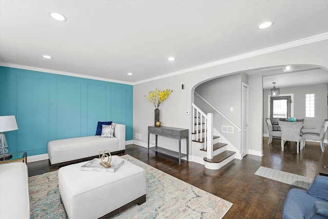 living room featuring arched walkways, recessed lighting, dark wood-style flooring, ornamental molding, and stairway