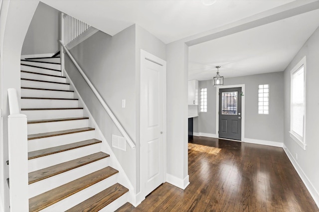 foyer with visible vents, dark wood finished floors, stairway, and baseboards