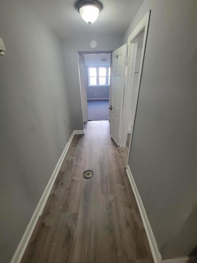 corridor featuring baseboards and wood finished floors