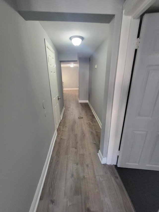 corridor with baseboards and wood finished floors