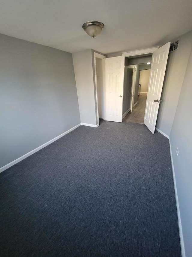 unfurnished bedroom with baseboards, visible vents, and dark colored carpet