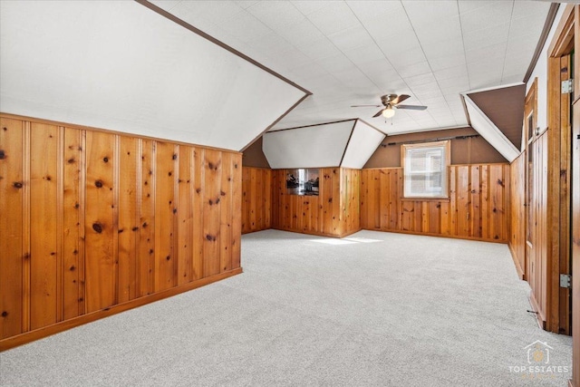 bonus room featuring vaulted ceiling, wooden walls, ceiling fan, and carpet floors