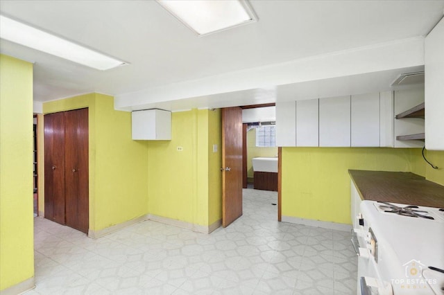 kitchen with open shelves, gas range gas stove, dark countertops, baseboards, and light floors