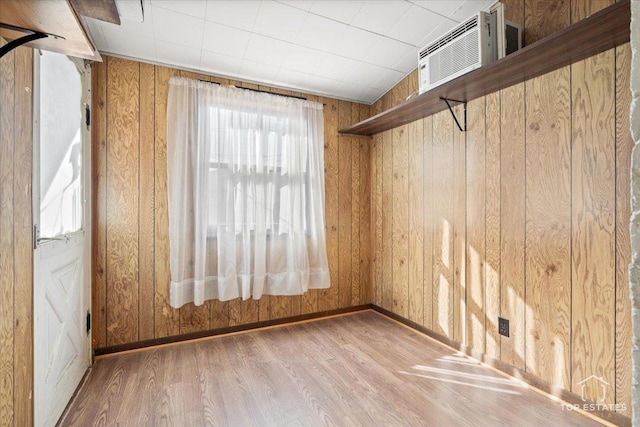 empty room featuring baseboards, wooden walls, and wood finished floors