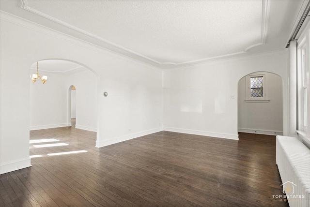 unfurnished room with baseboards, arched walkways, dark wood-type flooring, a textured ceiling, and crown molding