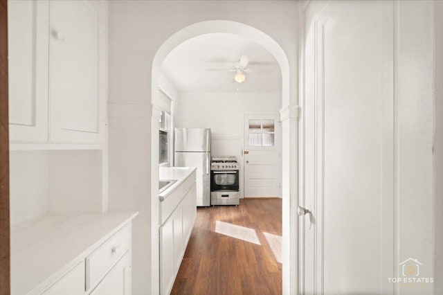 kitchen with range with gas stovetop, dark wood finished floors, freestanding refrigerator, light countertops, and white cabinets