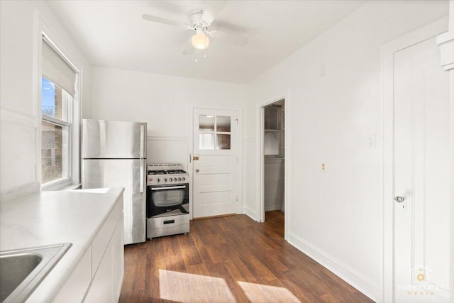 kitchen with dark wood-style flooring, a sink, light countertops, white cabinets, and appliances with stainless steel finishes