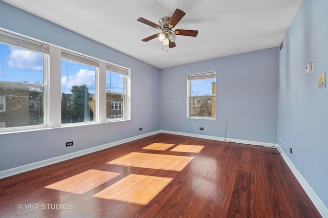 unfurnished room with a ceiling fan, wood finished floors, baseboards, and a wealth of natural light