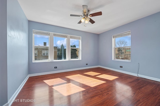 spare room with baseboards, wood finished floors, and a ceiling fan