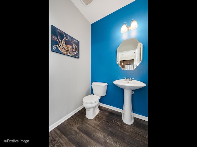 bathroom with toilet, wood finished floors, baseboards, and a sink