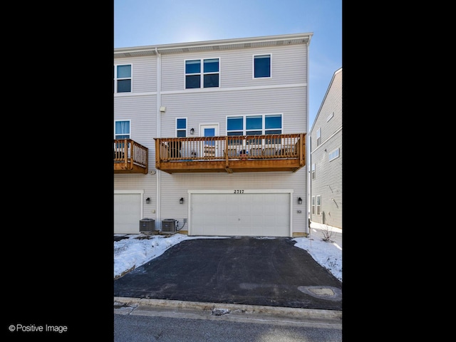 back of property with a garage, central air condition unit, and driveway