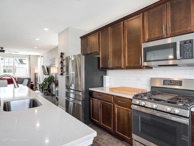 kitchen featuring dark wood finished floors, a sink, appliances with stainless steel finishes, tasteful backsplash, and open floor plan