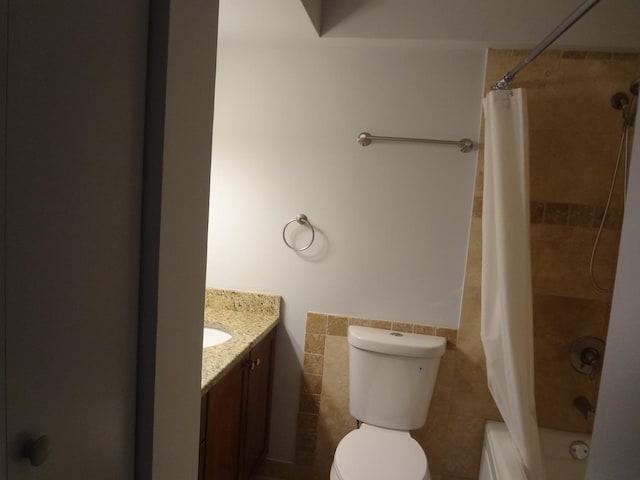 bathroom featuring toilet, a wainscoted wall, vanity, tile walls, and shower / tub combo with curtain