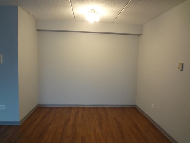 unfurnished room with a textured ceiling, baseboards, and wood finished floors