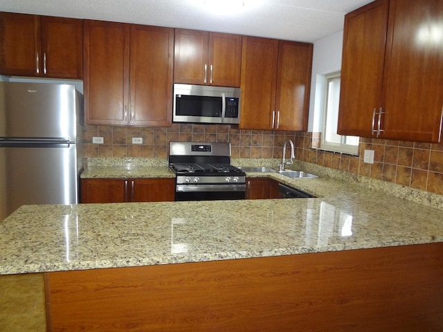 kitchen with stainless steel appliances, a sink, and light stone countertops