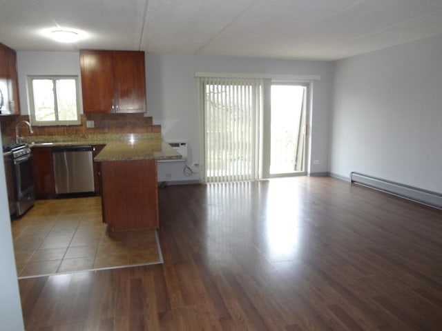 kitchen featuring stainless steel appliances, a peninsula, decorative backsplash, and wood finished floors