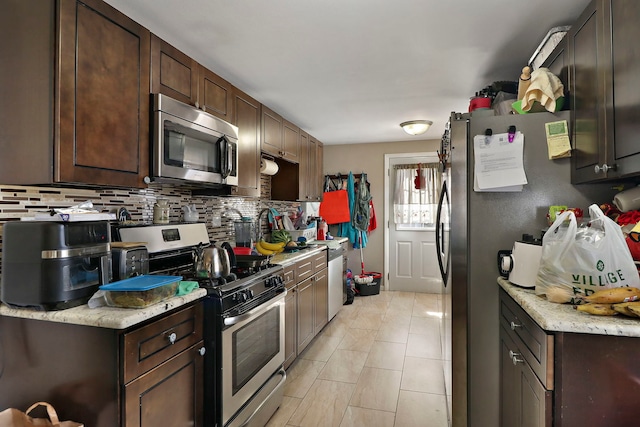 kitchen featuring light tile patterned floors, stainless steel appliances, dark brown cabinetry, and decorative backsplash