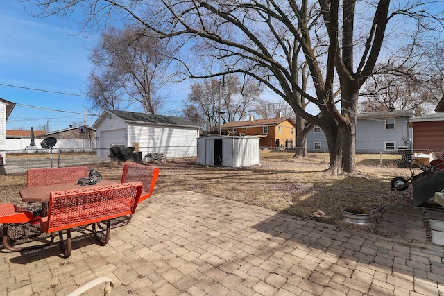 view of patio featuring outdoor dining area, a detached garage, an outdoor structure, and fence