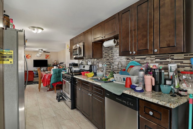 kitchen featuring a ceiling fan, a sink, dark brown cabinetry, appliances with stainless steel finishes, and decorative backsplash