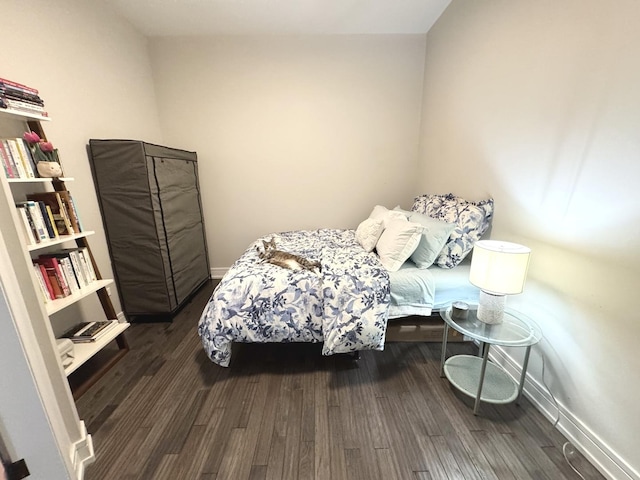 bedroom with baseboards and dark wood-type flooring