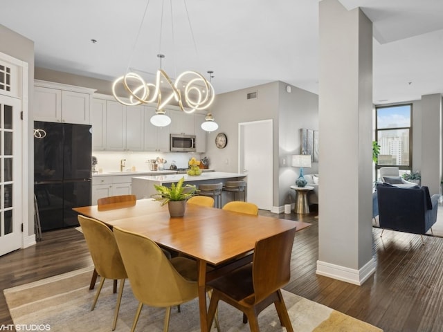 dining area with an inviting chandelier, wood finished floors, visible vents, and baseboards