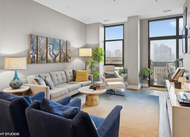 living area with expansive windows, a city view, and wood finished floors